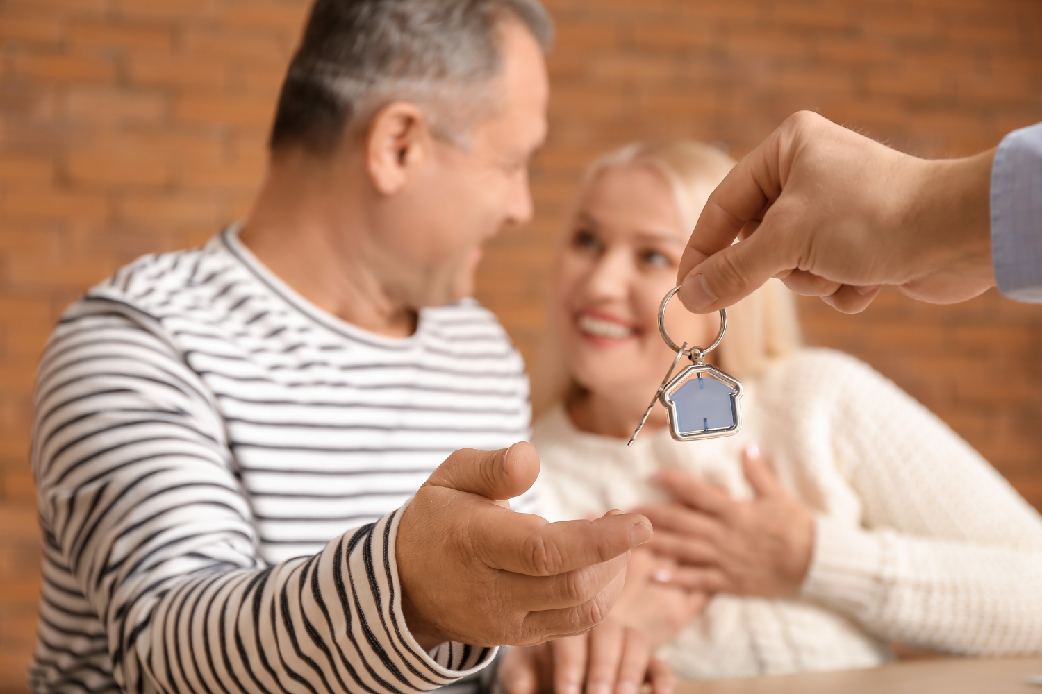 Real estate agent giving a key from new house to mature couple, closeup